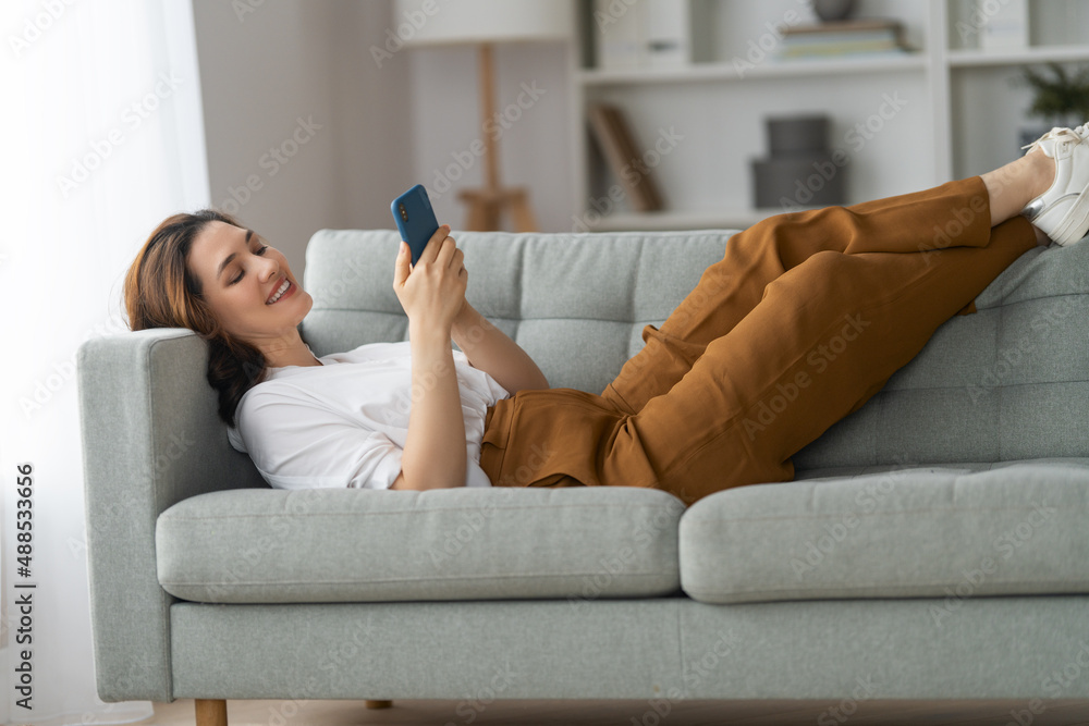 woman is using a phone sitting on a sofa