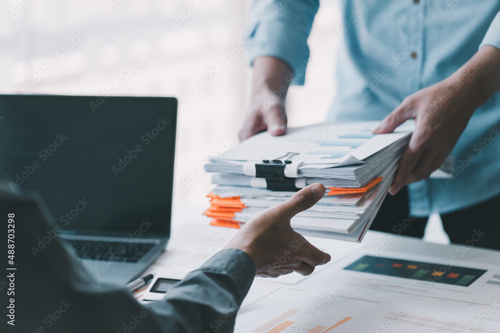 A young business man in a suit is managing paperwork in the office. Many paperwork that is not finis