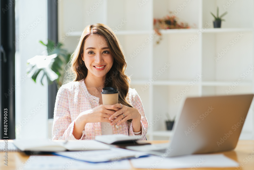 Portrait young attractive beautiful asia female sit on desk smile to camera work at home remotely co