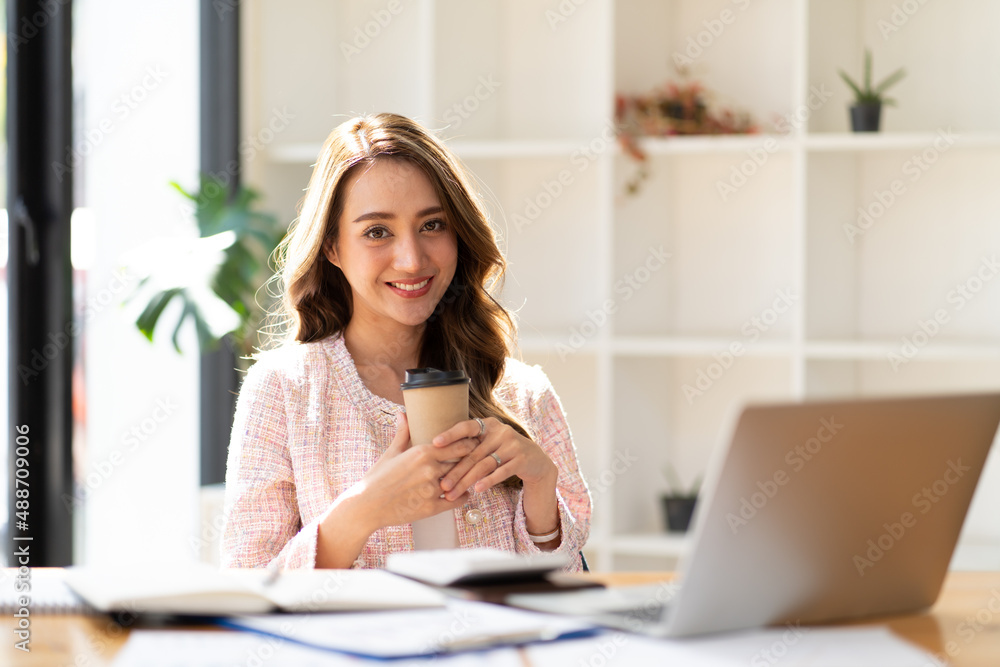 Portrait young attractive beautiful asia female sit on desk smile to camera work at home remotely co