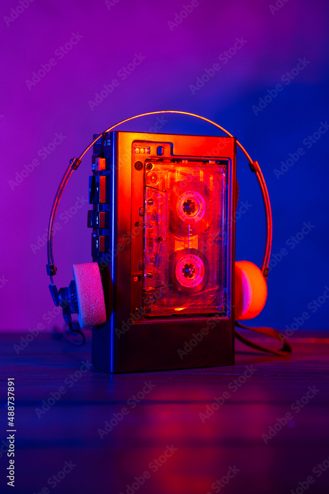 Vintage cassette tape player in neon light. 80s - 90s advertisement style. Disco party nostalgy conc