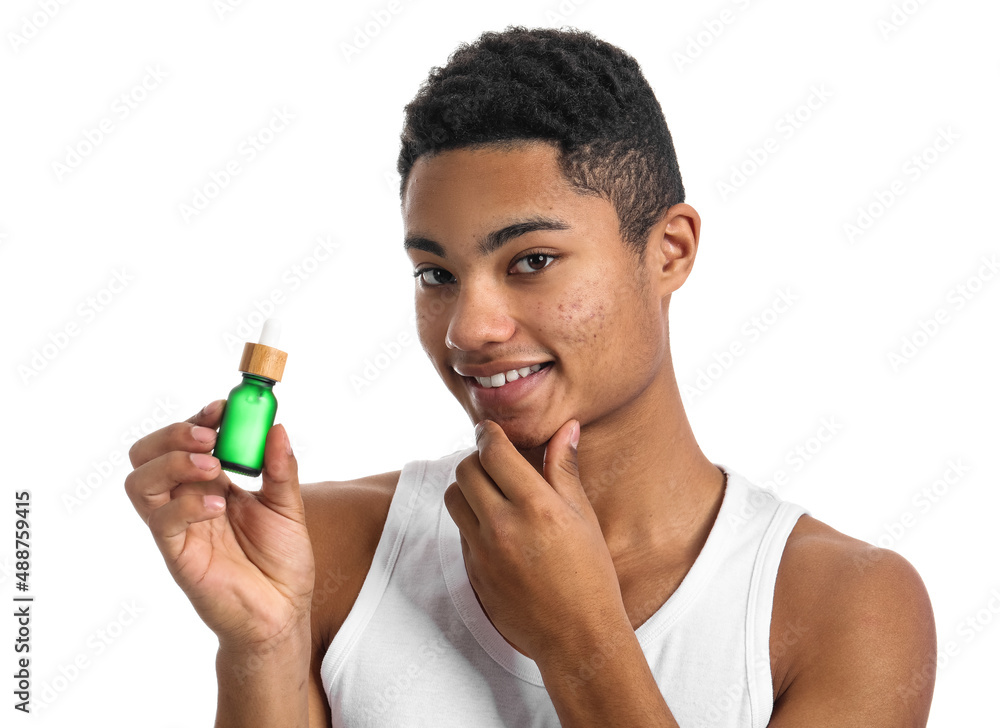 Young African-American guy with serum for skin care on white background