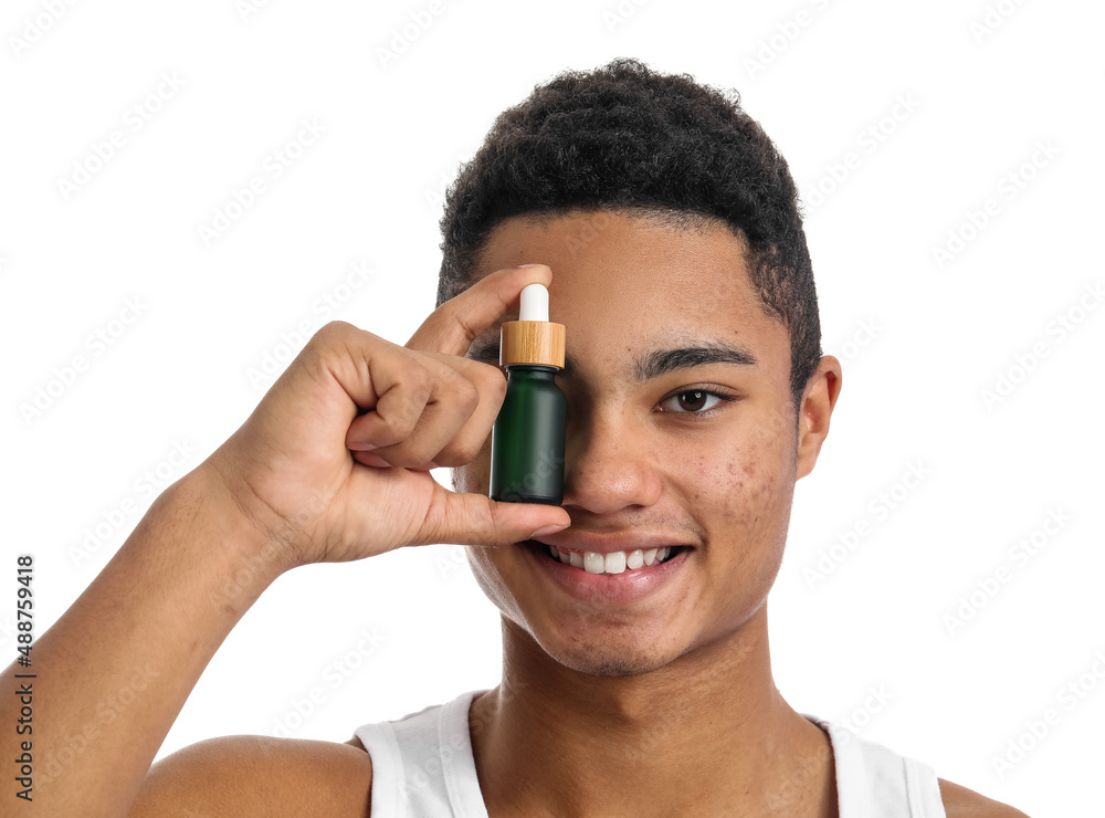 Young African-American guy with serum for skin care on white background