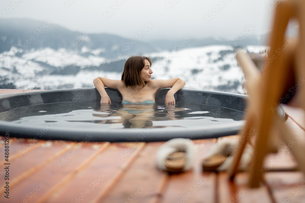 年轻女子冬天在山上的热水浴缸里洗澡。在热水浴缸里休息和恢复的概念