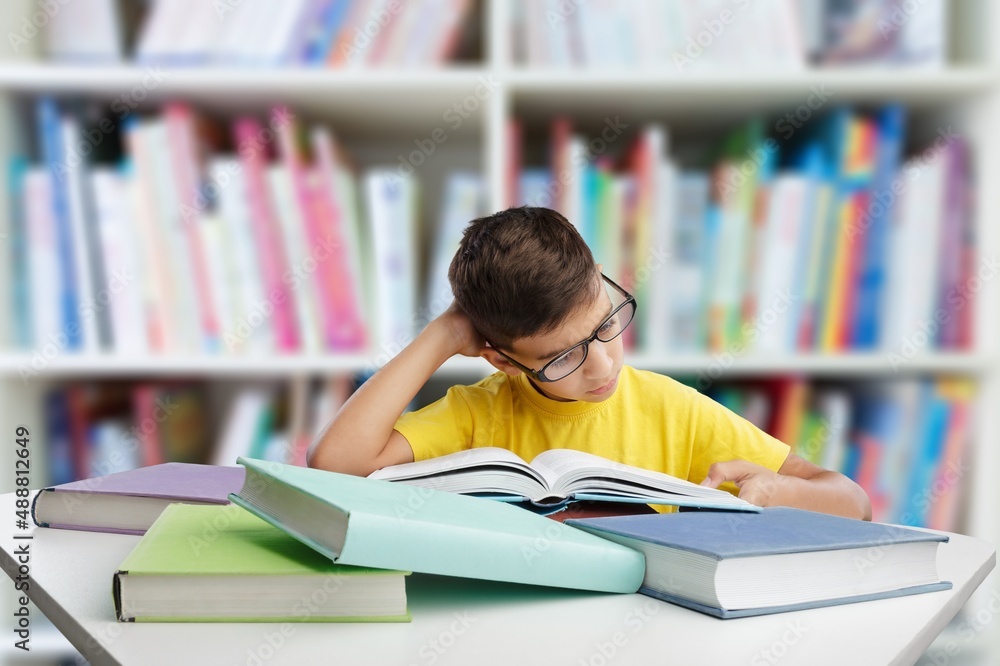 Exhautsed kid teen doing homework alone, sitting at table full of exercise books,