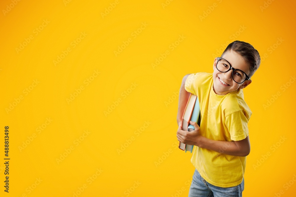 Happy school boy wearing glasses, holding backpack going to school, enjoying studying,