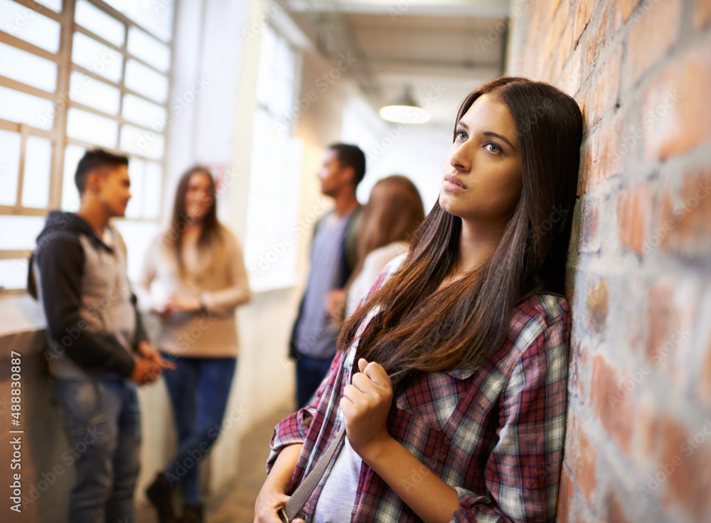 Loving life on campus. Shot of a beautiful young female student looking bored while leaning against 