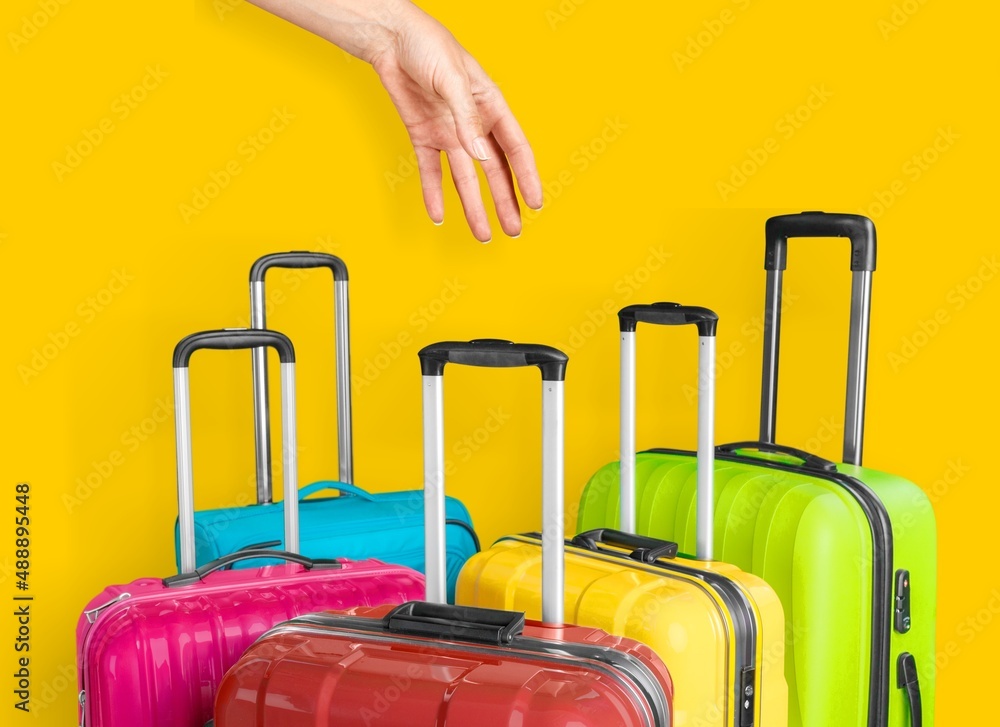 Female hand holds a suitcase on a bright yellow background