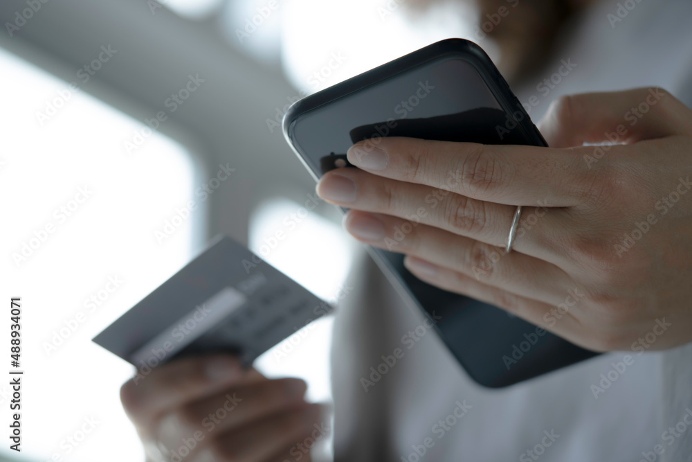 Female hands holding credit card and using smartphone. Online shopping