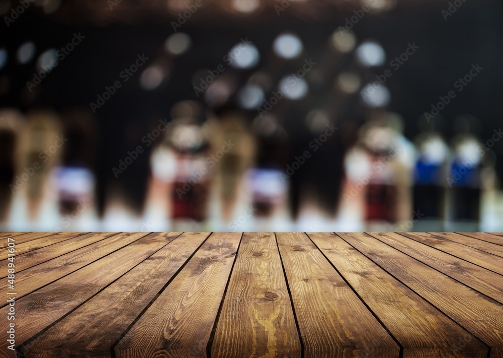 Blank table top and beautiful bokeh shelves with alcohol bottles on the background. Bar concept.