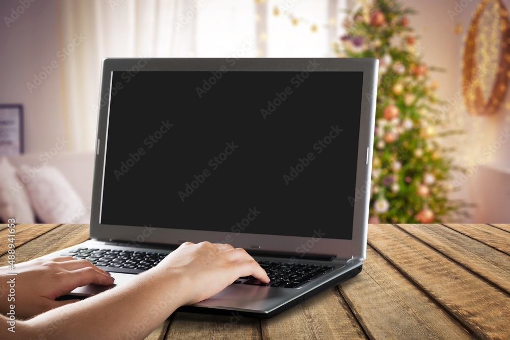 Person work on laptop computer with a blank display screen. home interior decorated for Christmas