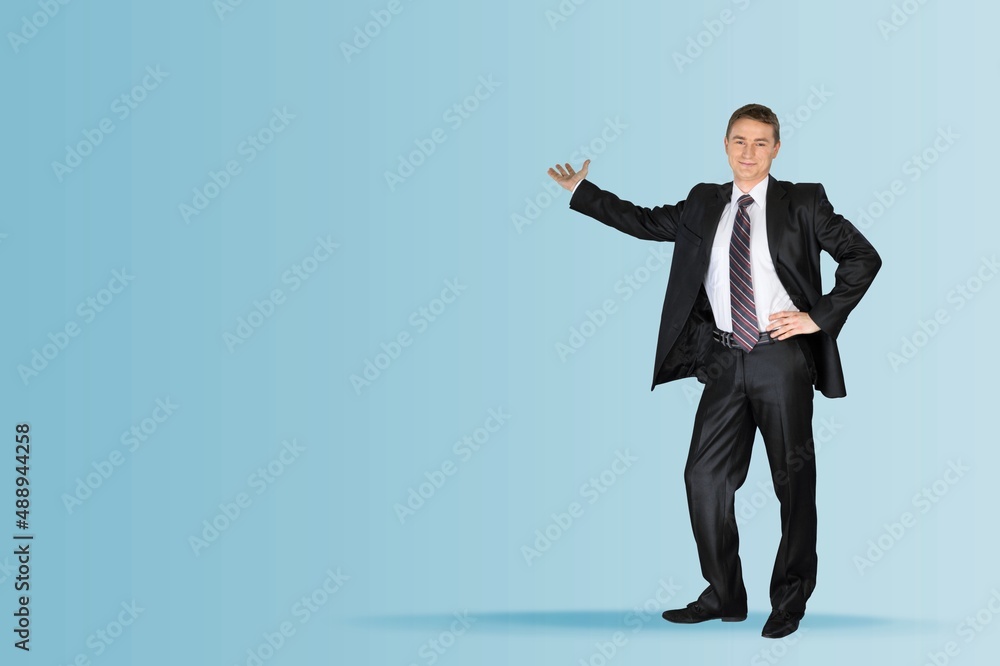 Happy young handsome businessman pointing to copy space on background