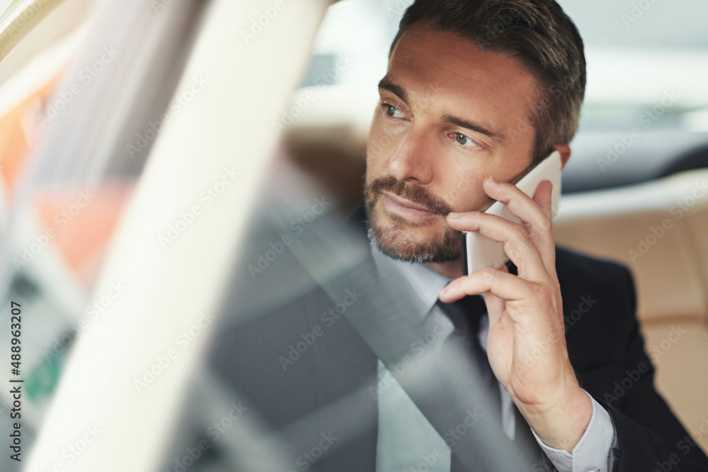 Staying connected in commute. Shot of a businessman using his phone while traveling in a car.