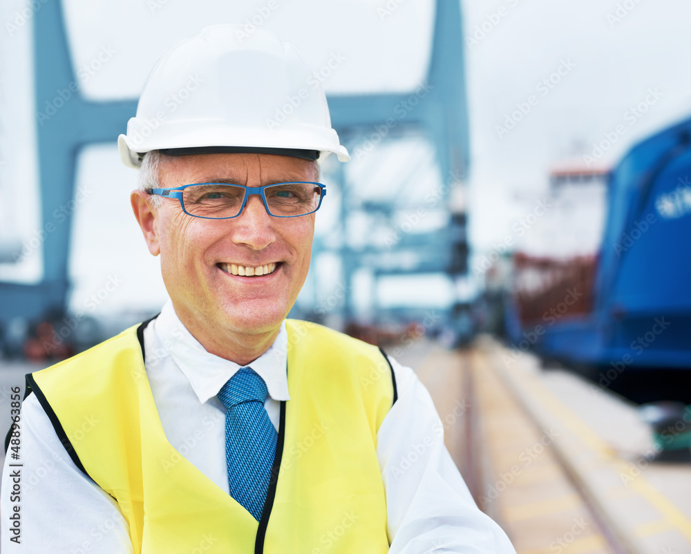 Smiling marine surveyor. Portrait of a dock worker standing at the harbor amidst shipping industry a