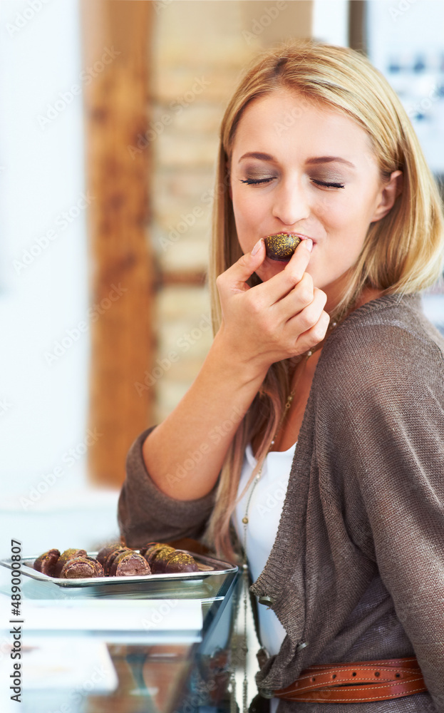 嗯，这味道太棒了。漂亮的年轻女人在商店里咬着巧克力样品。