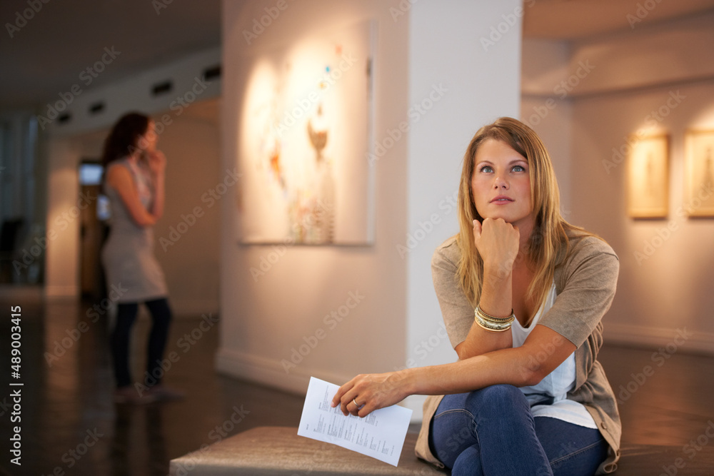 Pondering the paintings themes. Two young friends looking at paintings while attending an exhibition