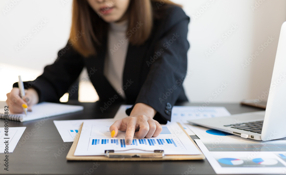 Businessmanwoman on office desk pointing at a paperwork is analyzing and auditing.