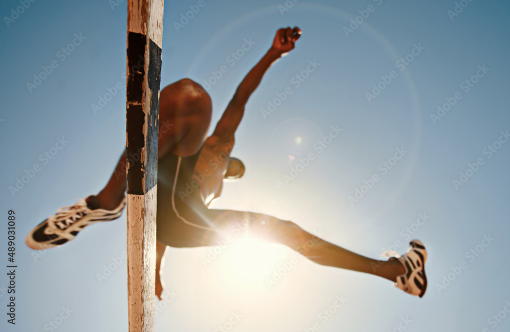 Know your limitations and defy them. Low angle shot of an athletic practicing high jump.