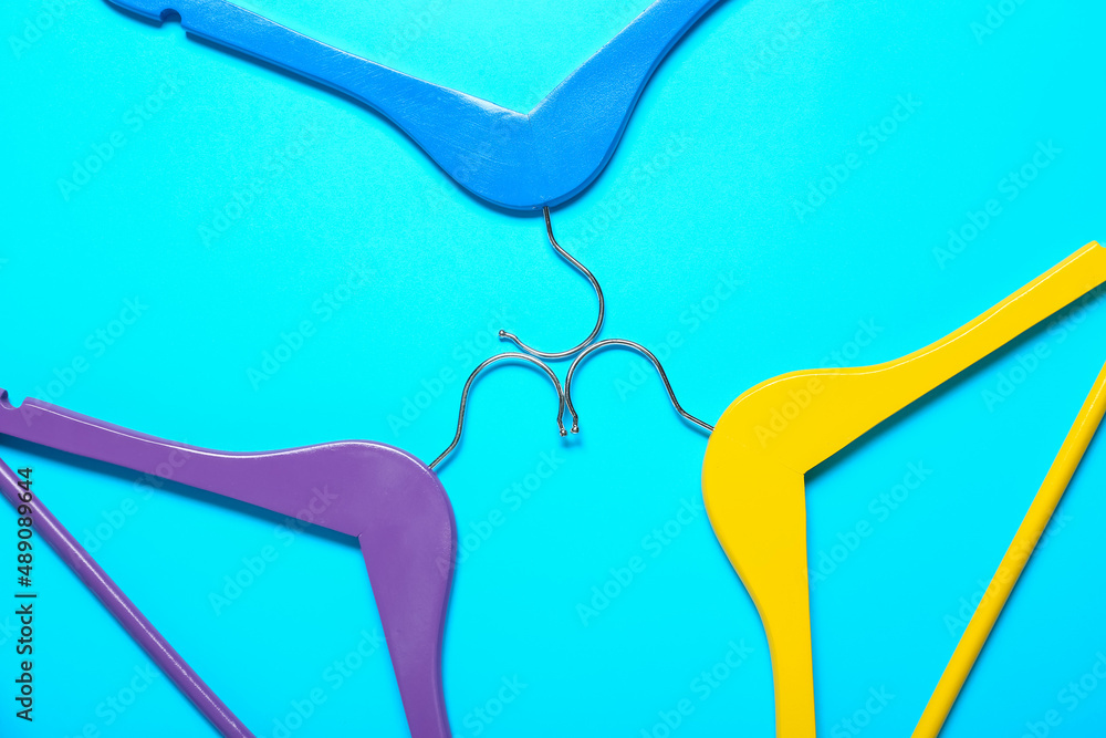 Bright clothes hangers on color background