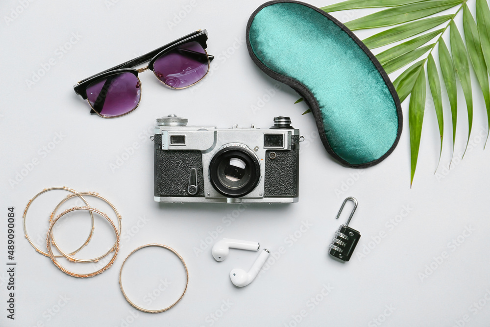 Composition with female accessories, photo camera, earphones and sleeping mask on white background