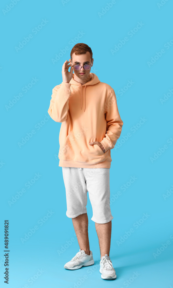 Young guy in stylish hoodie on color background