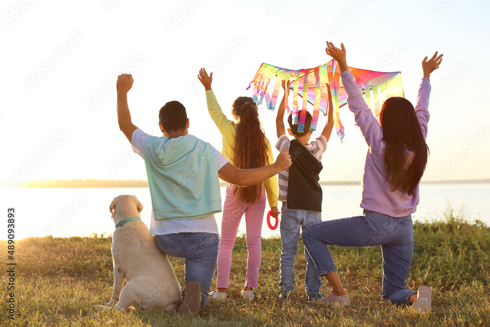 Happy family with kite and cute dog near river