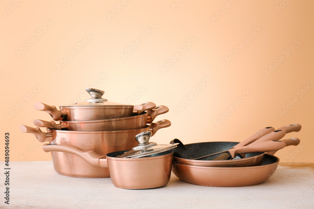 Set of copper utensils on table against color background