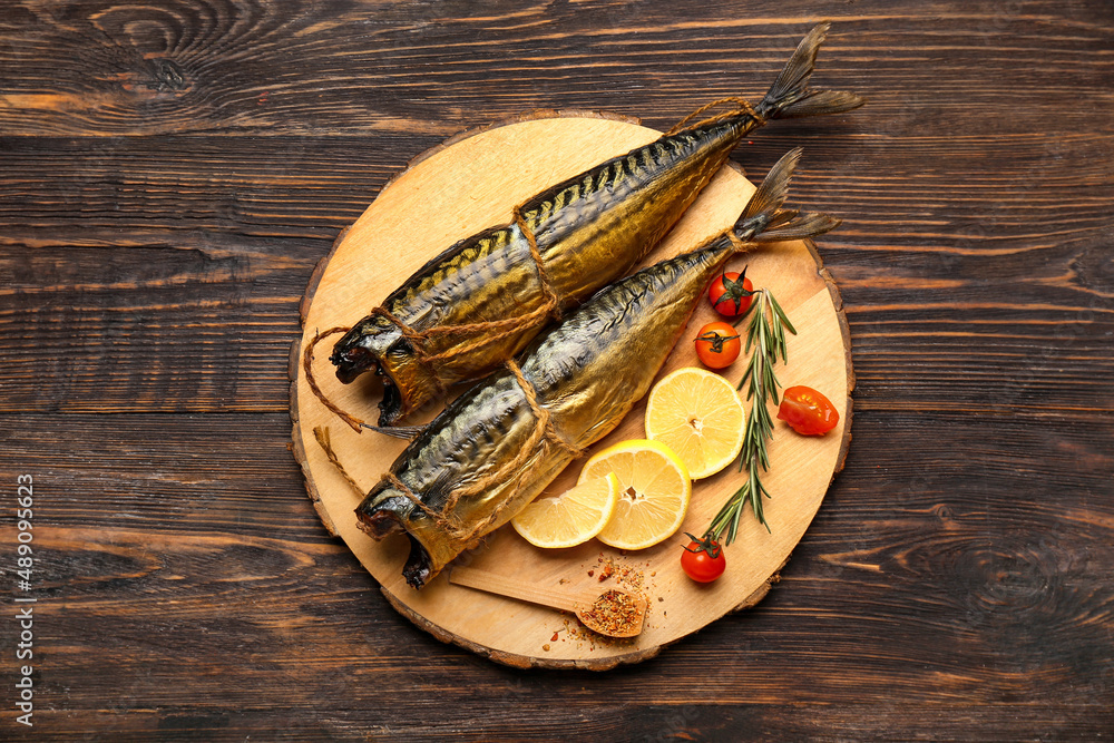 Board with tasty smoked mackerel fishes on dark wooden background