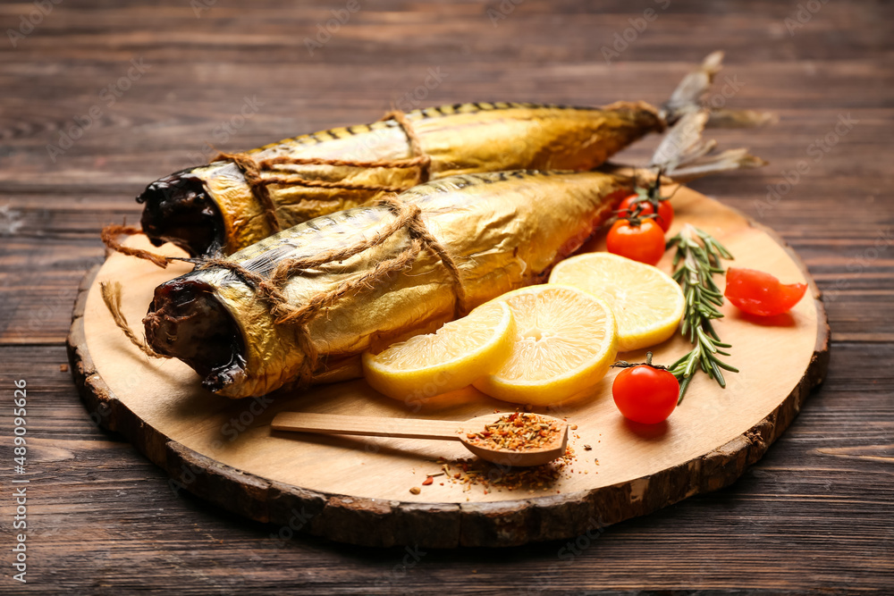 Board with tasty smoked mackerel fishes on dark wooden background