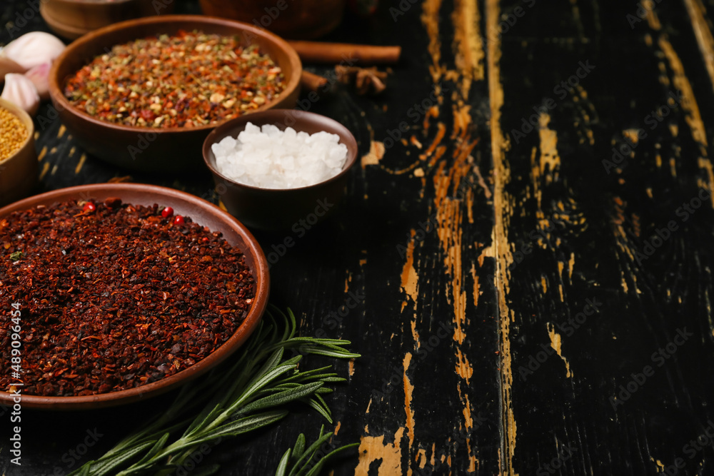 Bowls of aromatic spices on dark wooden background, closeup