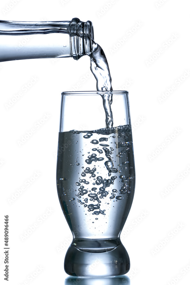 Pouring of clear water in glass isolated on white