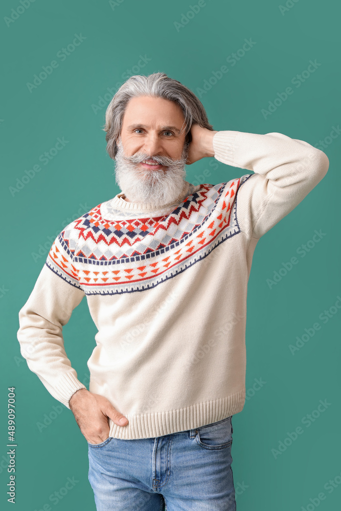 Handsome senior man in knitted sweater on green background