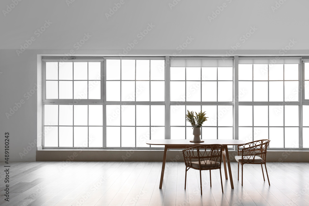 Table with vase and chairs in big empty room