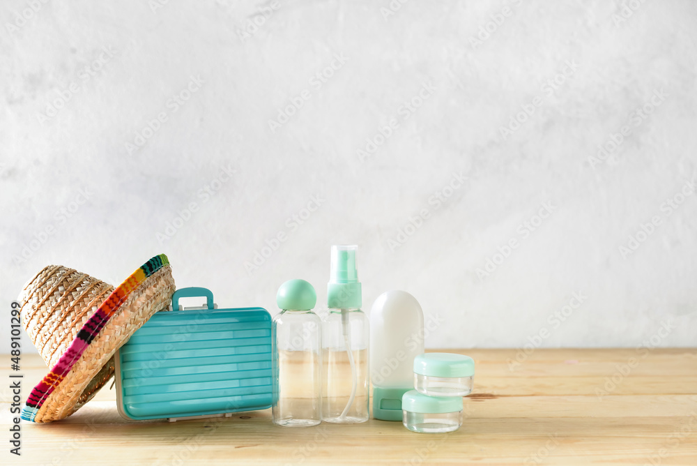 Composition with empty travel bottles, jars and sombrero on wooden table