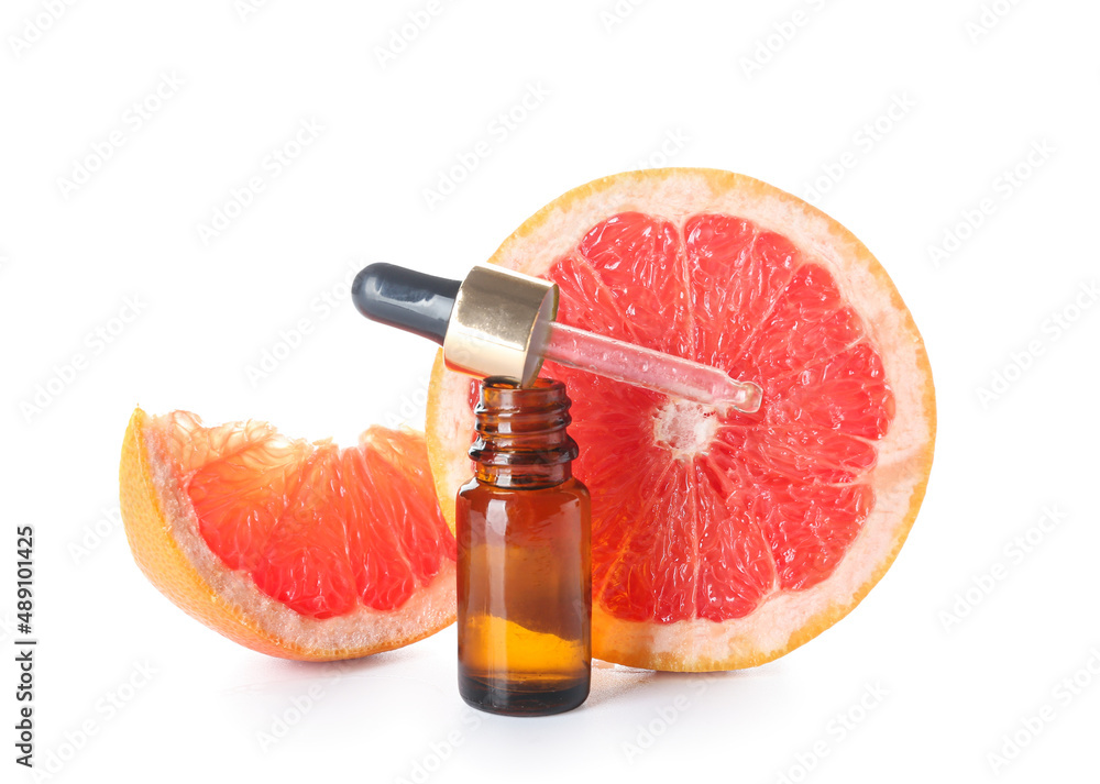 Bottle of essential oil and juicy grapefruit isolated on white background