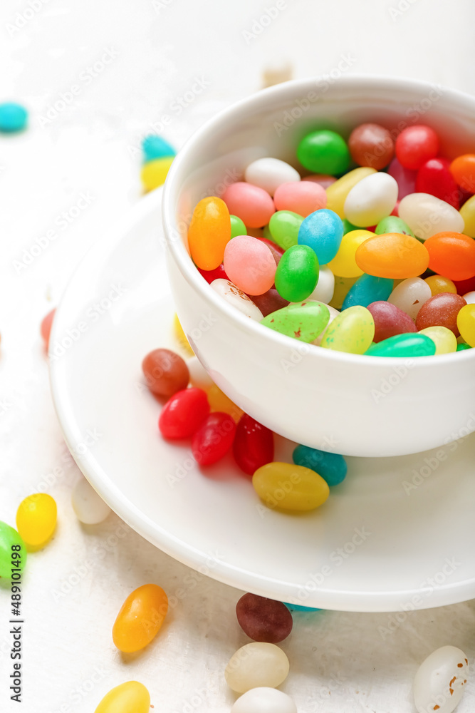 Cup with different jelly beans on light background, closeup