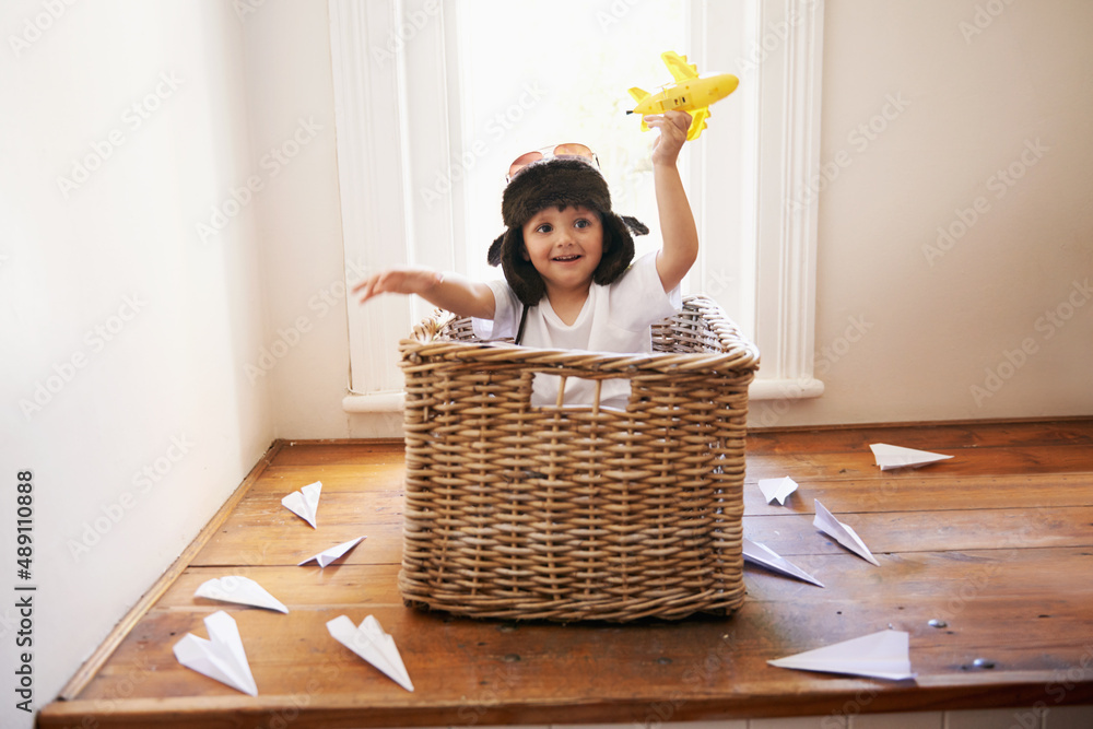 Let your imagination take flight. A little boy playing with toy airplanes while sitting in a basket.