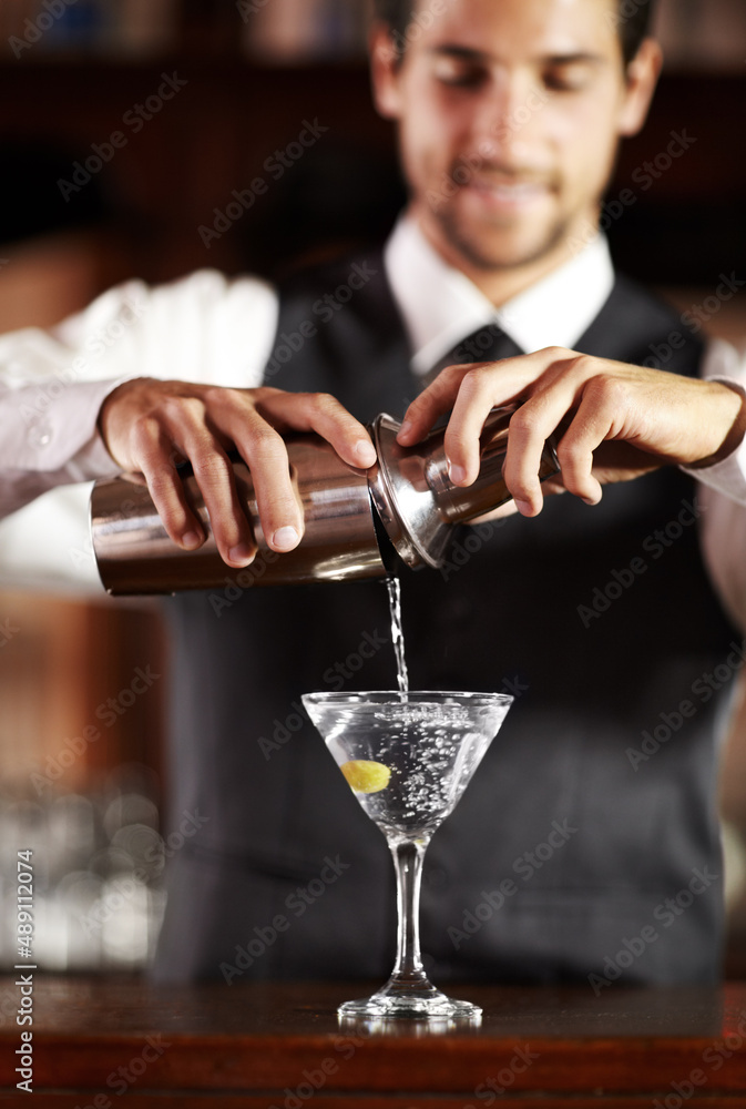 Shaken not stirred. Shot of a handsome young bartender mixing a cocktail.