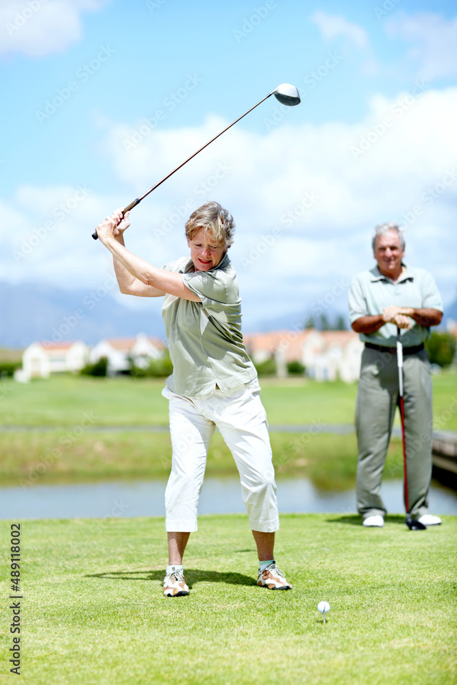 She has perfected her swing over the years. Image of a mature woman in full swing during a game of g