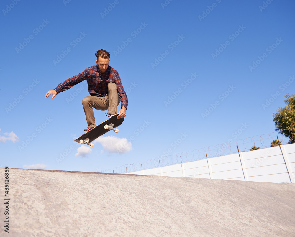 Perfecting his tricks. A young man doing tricks on his skateboard at the skate park.