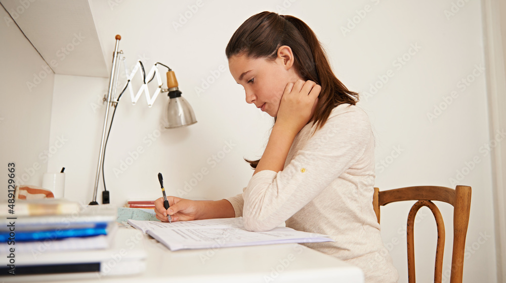 Getting it all in her head. Shot of a young woman studying at her desk at home.