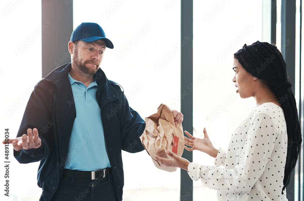 Im sorry but theres nothing I can do about this. Shot of a handsome delivery man negotiating with a 