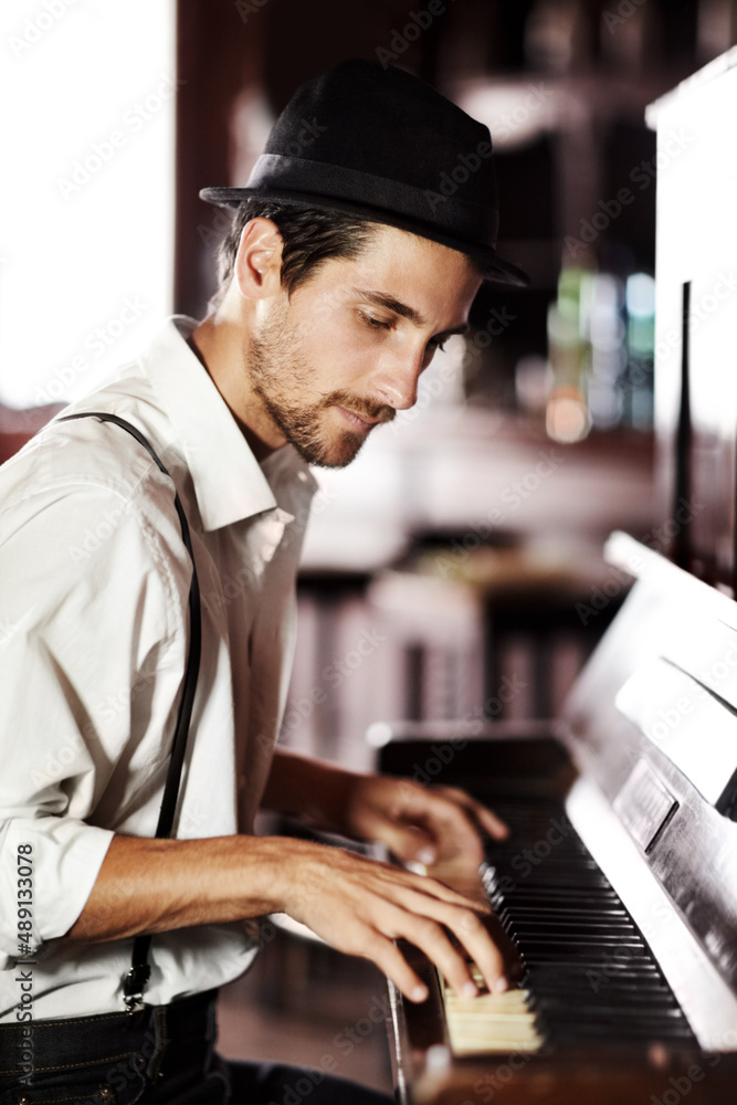 Expressing the music from deep within his soul. A handsome young man playing the piano in a club.