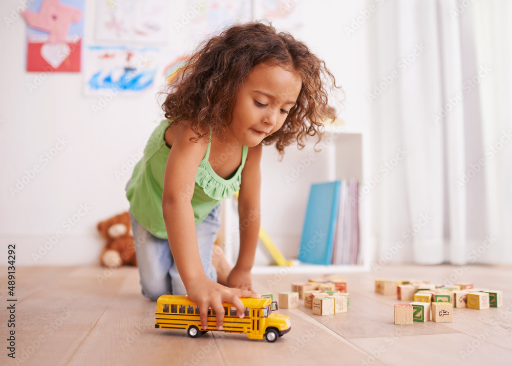 Vroom goes the school bus. Shot of a little girl playing with a toy truck and building blocks.