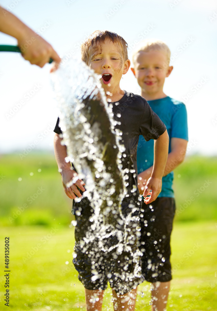 They dont need a pool to cool off. Little boys getting wet by a hose pipe while outdoors.