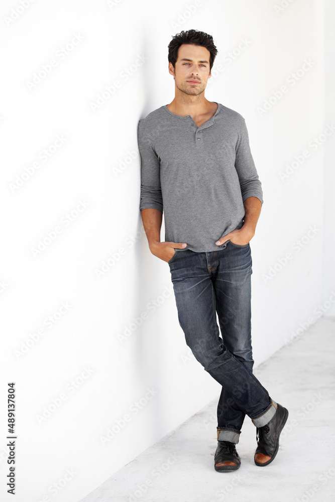 Hes got style. Portrait of a handsome young man leaning against a wall with his hands in his pockets