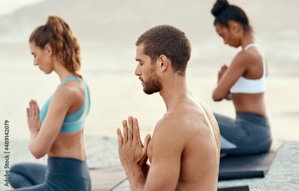 Take the moment to be present and at peace. Shot of a group of young people practicing yoga together