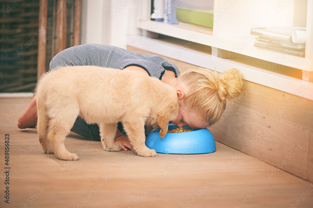 Friends forever...you eat, I eat. An adorable little girl sharing a bowl of food with her puppy at h