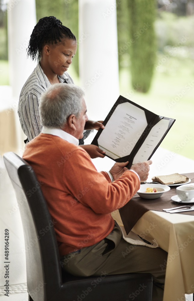 Showing him the specials. A senior man being shown the specials on a menu by his waitress.