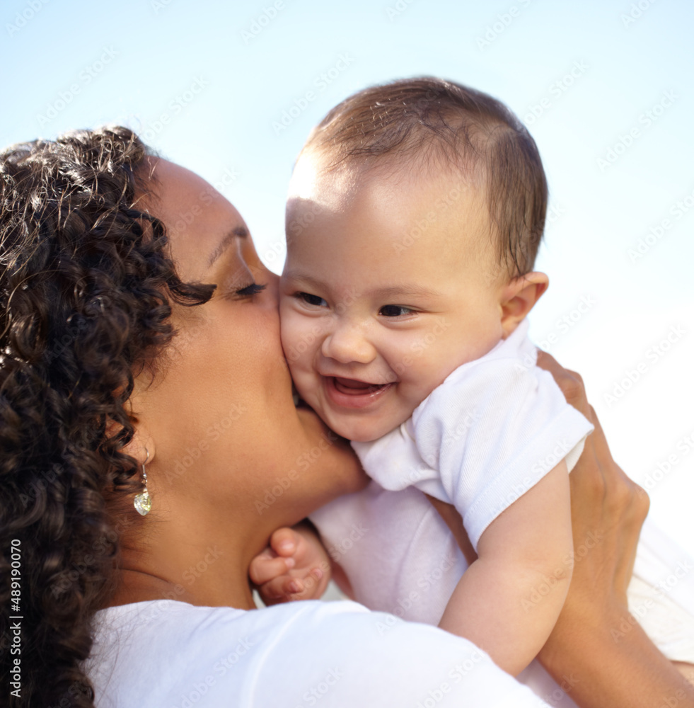 Happy times. Closeup of a young mother holding up and kissing her baby daughter.